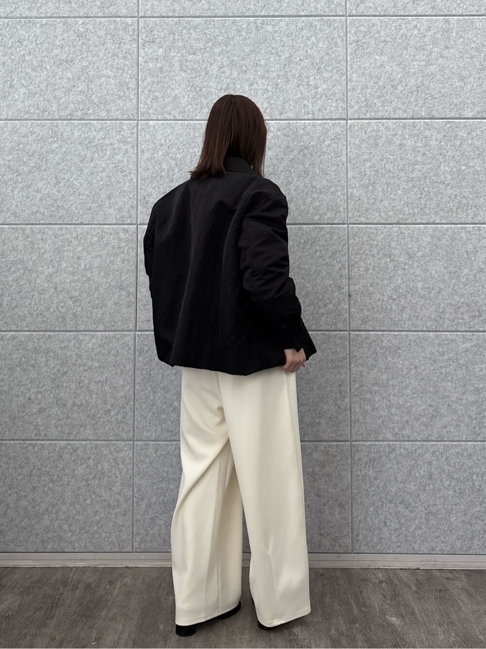グレー系のニット/セーター、ブラック系のブルゾン、ホワイト系のその他パンツを着用したレディースの秋コーディネートの5枚目の写真