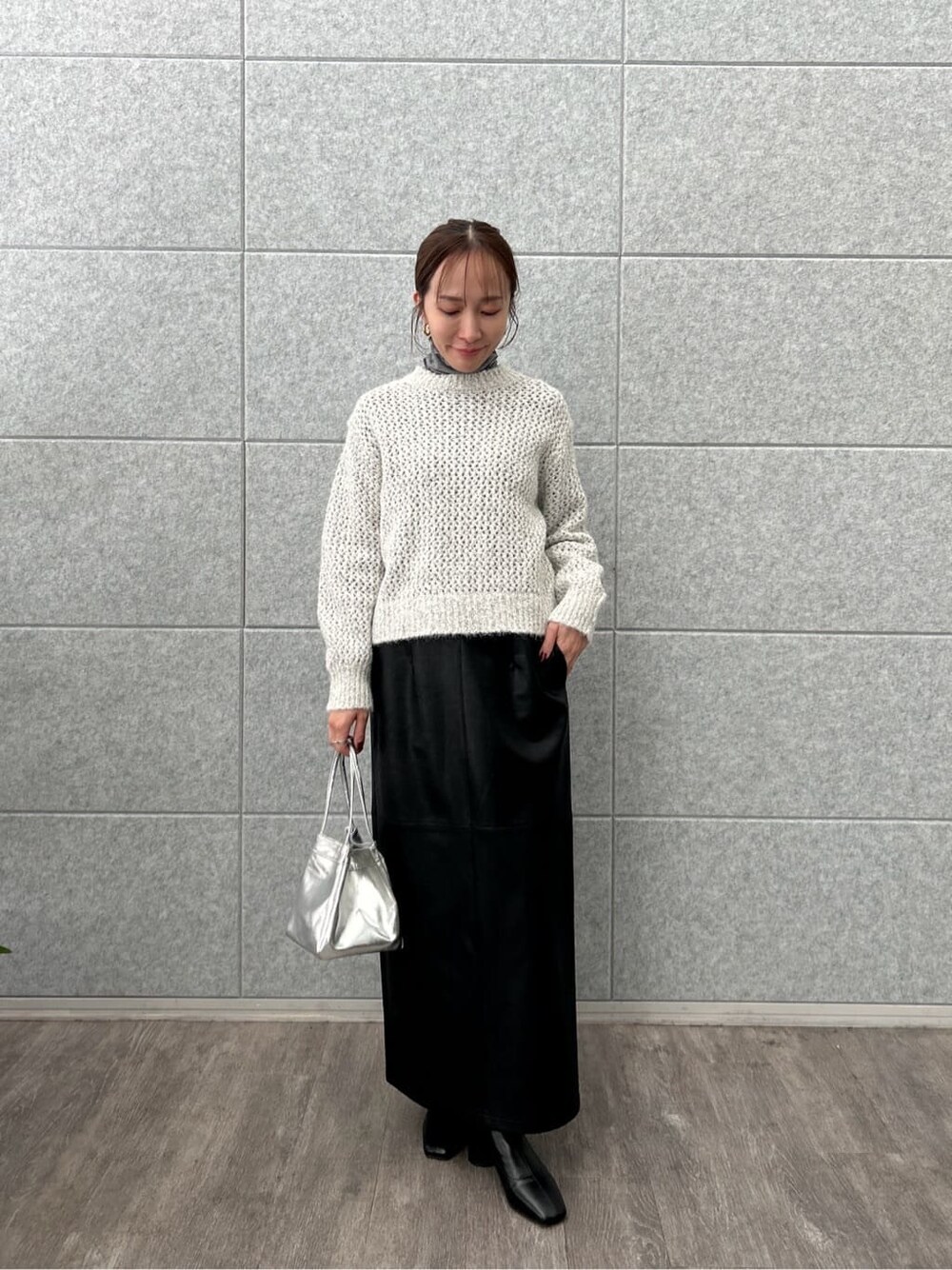 グレー系のニット/セーター、グレー系のTシャツ/カットソー、ブラック系のスカートを着用したレディースの冬コーディネートの2枚目の写真