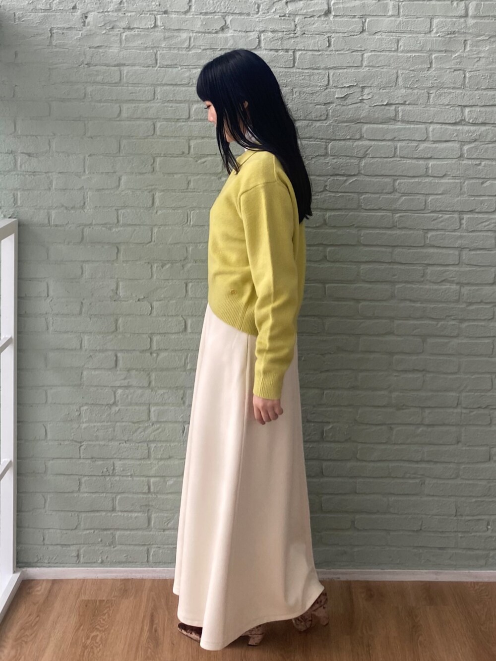 ホワイト系のTシャツ/カットソー、ホワイト系のスカート、イエロー系のニット/セーターを着用したレディースの秋コーディネートの3枚目の写真