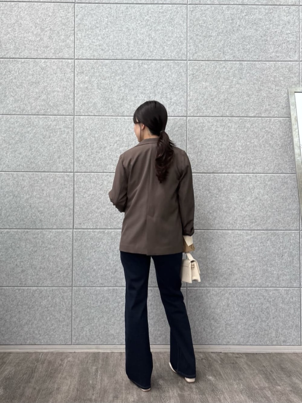 ブラウン系のテーラードジャケット、ブルー系のデニムパンツ、ホワイト系のニット/セーターを着用したレディースの秋コーディネートの3枚目の写真