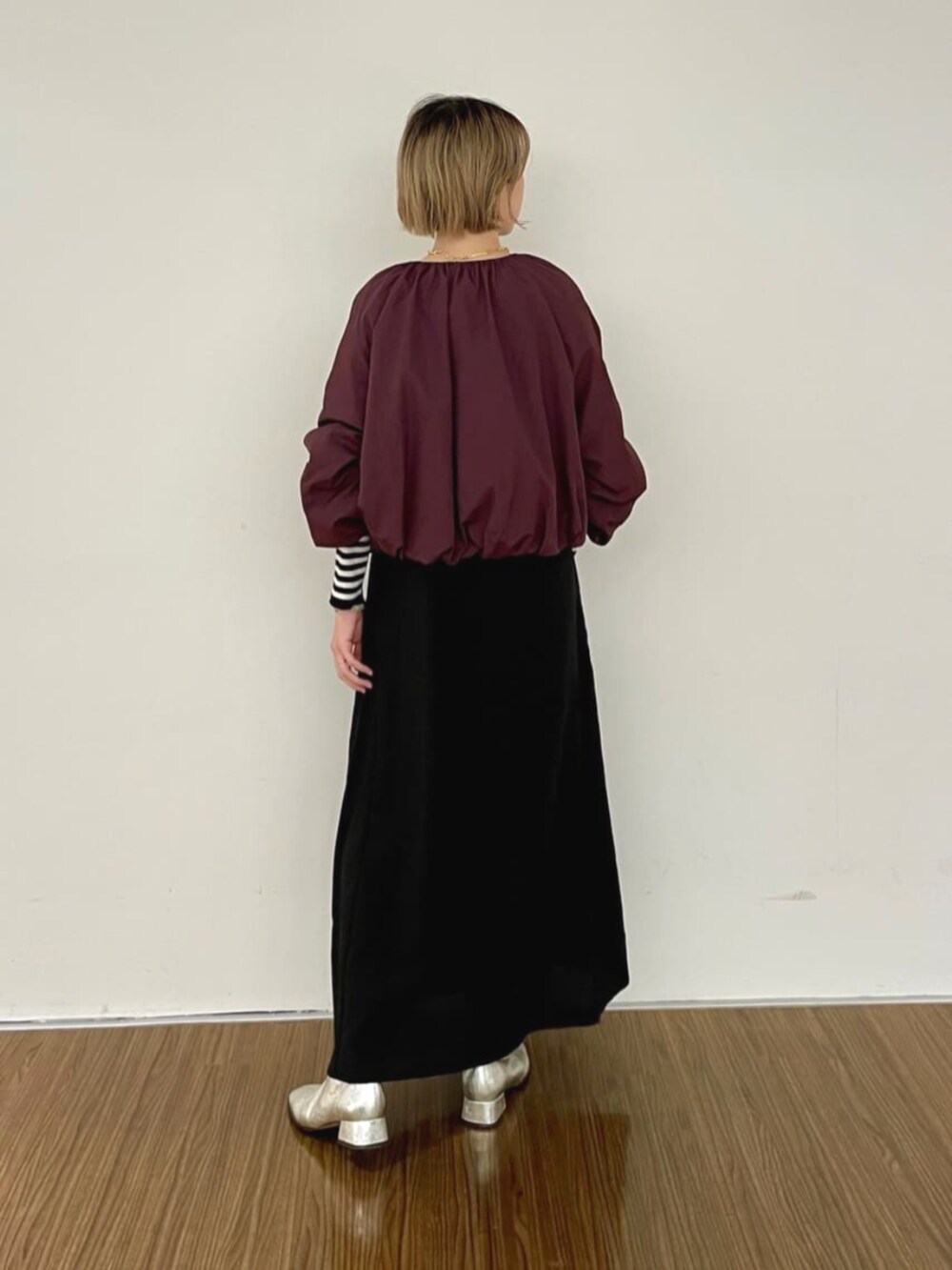 レッド系のブルゾン、ブラック系のワンピース、ベージュ系のニット/セーターを着用したレディースの秋コーディネートの4枚目の写真