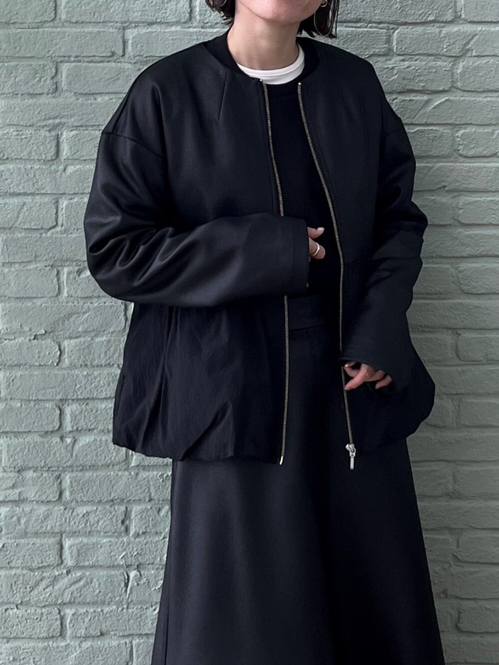 ブラック系のスカート、ブラック系のブルゾン、ブラック系のスウェットを着用したレディースの秋コーディネートの5枚目の写真