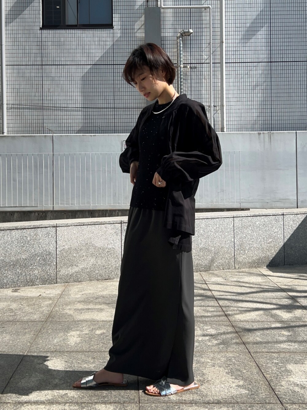 ブラック系のニット/セーター、グレー系のスカート、ブラック系のシャツ/ブラウスを着用したレディースの春コーディネートの4枚目の写真