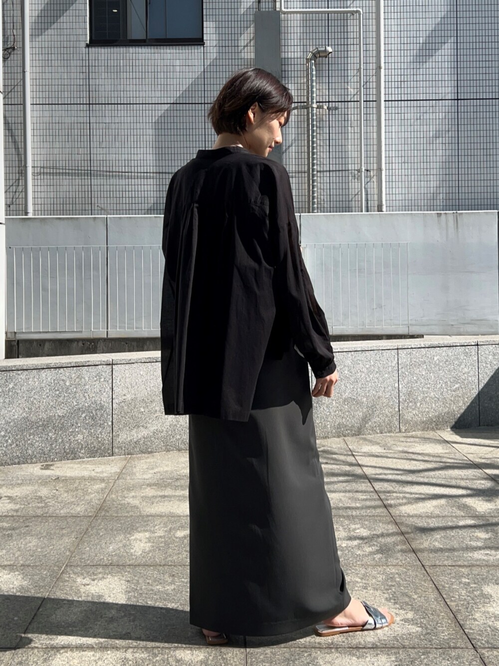 ブラック系のニット/セーター、グレー系のスカート、ブラック系のシャツ/ブラウスを着用したレディースの春コーディネートの5枚目の写真