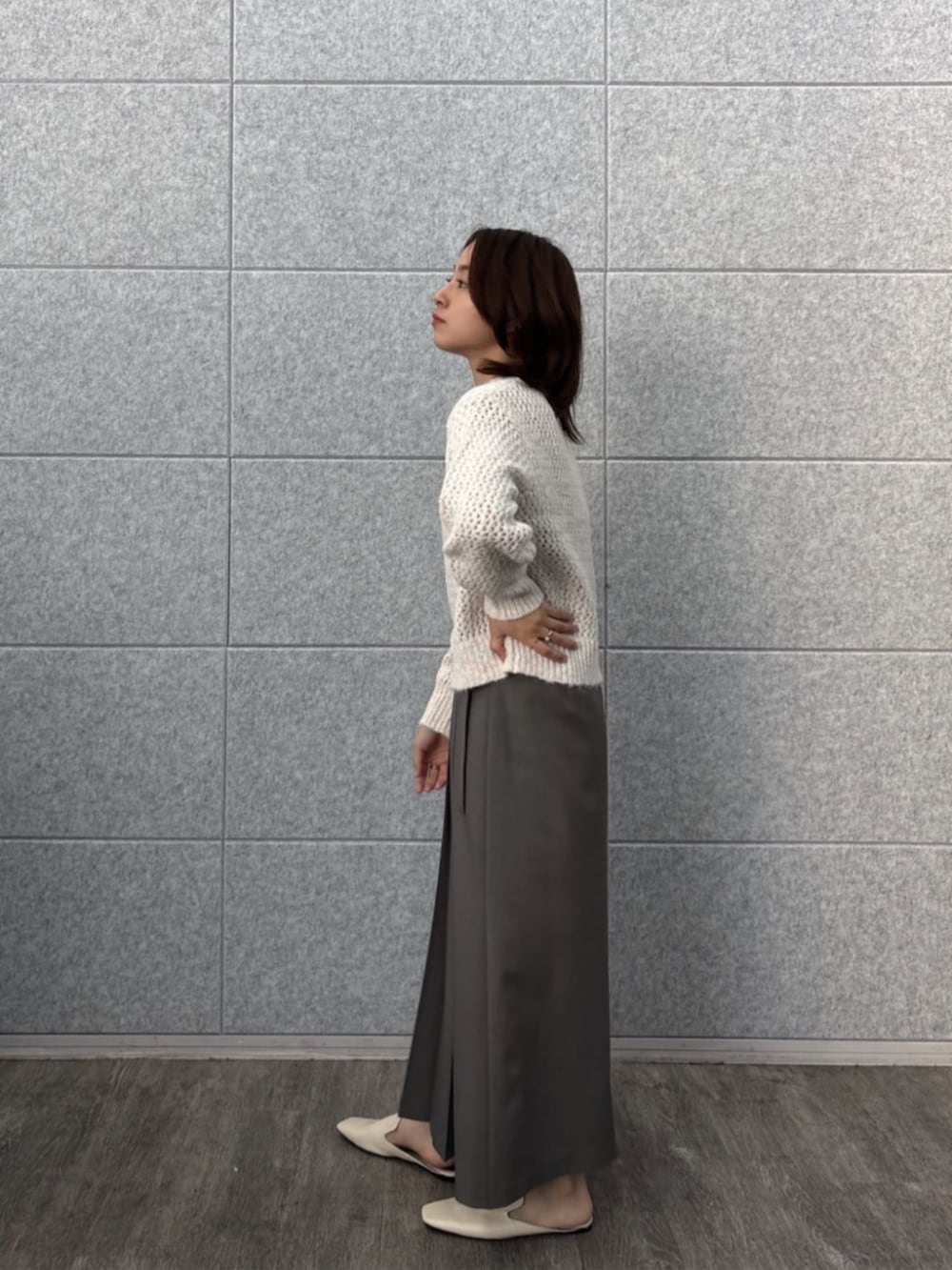 グレー系のスカート、ホワイト系のニット/セーターを着用したレディースの秋コーディネートの2枚目の写真