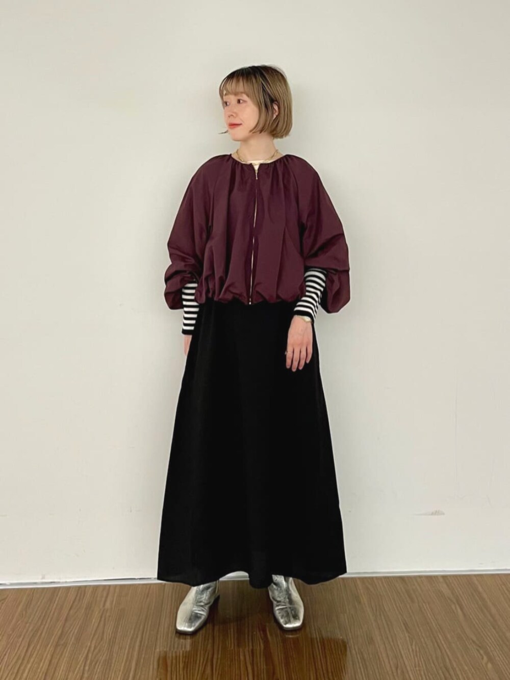 レッド系のブルゾン、ブラック系のワンピース、ベージュ系のニット/セーターを着用したレディースの秋コーディネートの3枚目の写真