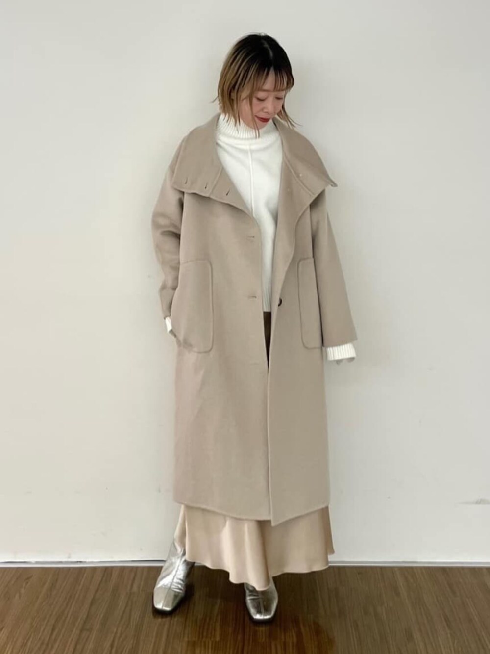 ベージュ系のスカート、ホワイト系のニット/セーター、ベージュ系のその他アウターを着用したレディースの秋コーディネートの2枚目の写真