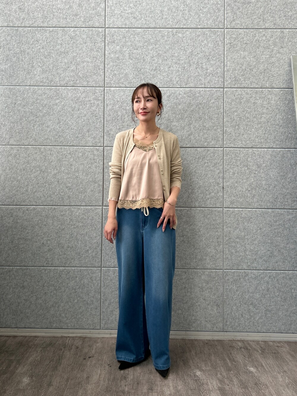 ベージュ系のカーディガン/ボレロ、ベージュ系のタンクトップ、ブルー系のデニムパンツを着用したレディースの秋コーディネートの2枚目の写真