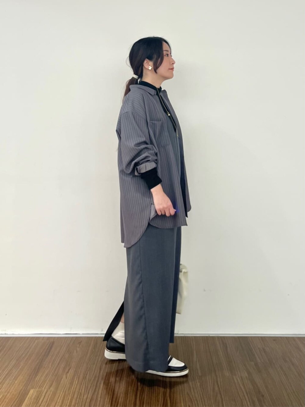 グレー系のシャツ/ブラウス、グレー系のワンピース、ブラック系のTシャツ/カットソーを着用したレディースの秋コーディネートの2枚目の写真