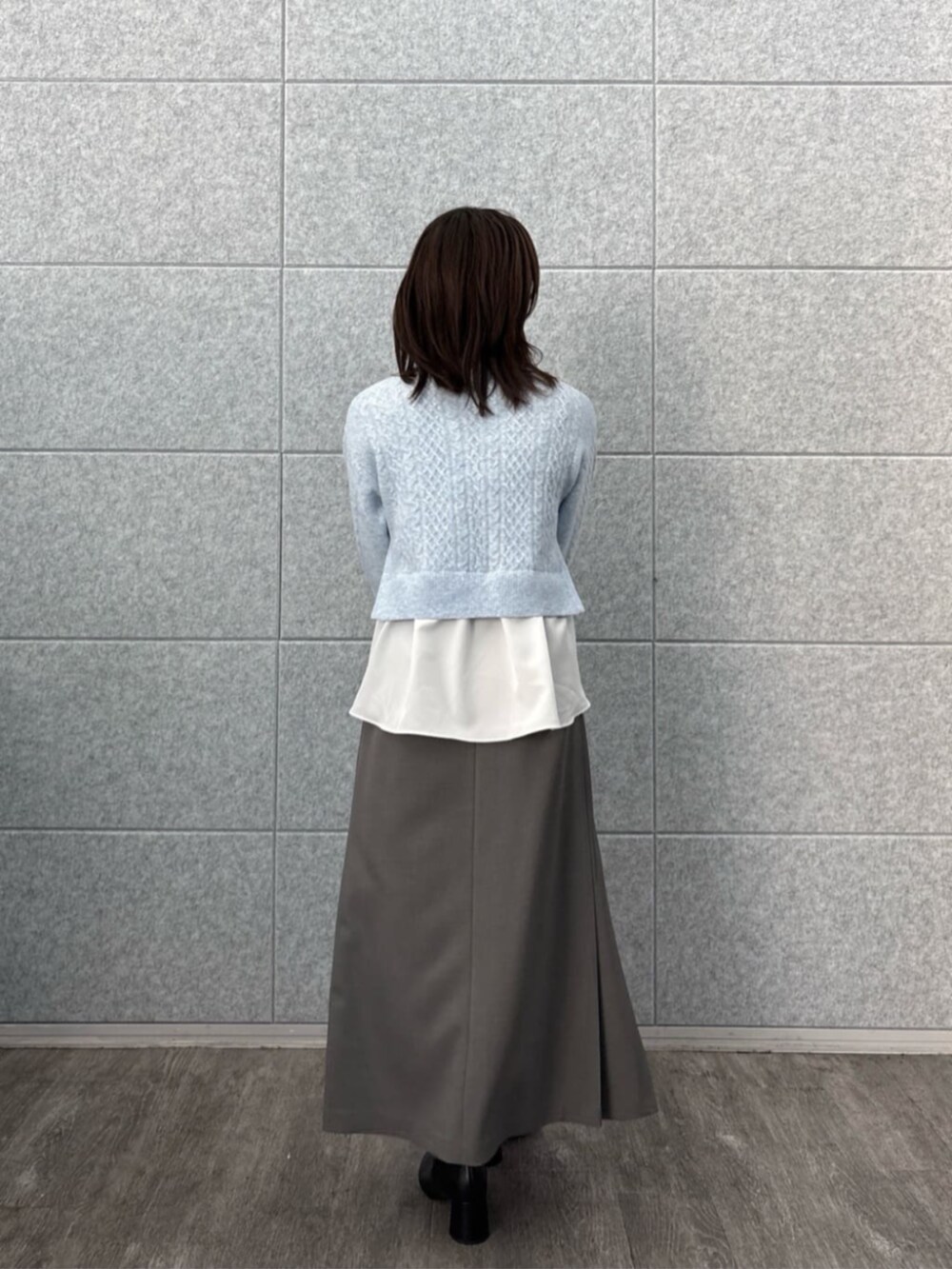 ブルー系のニット/セーター、グレー系のスカートを着用したレディースの秋コーディネートの2枚目の写真