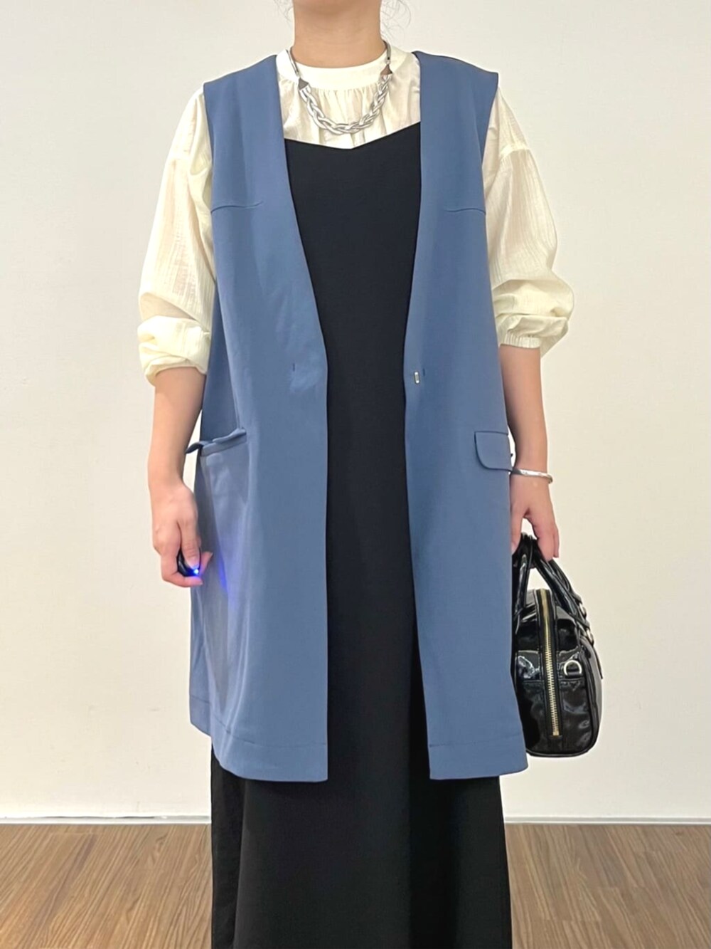 ブラック系のワンピース、ブルー系のベスト、ホワイト系のシャツ/ブラウスを着用したレディースの秋コーディネートの6枚目の写真