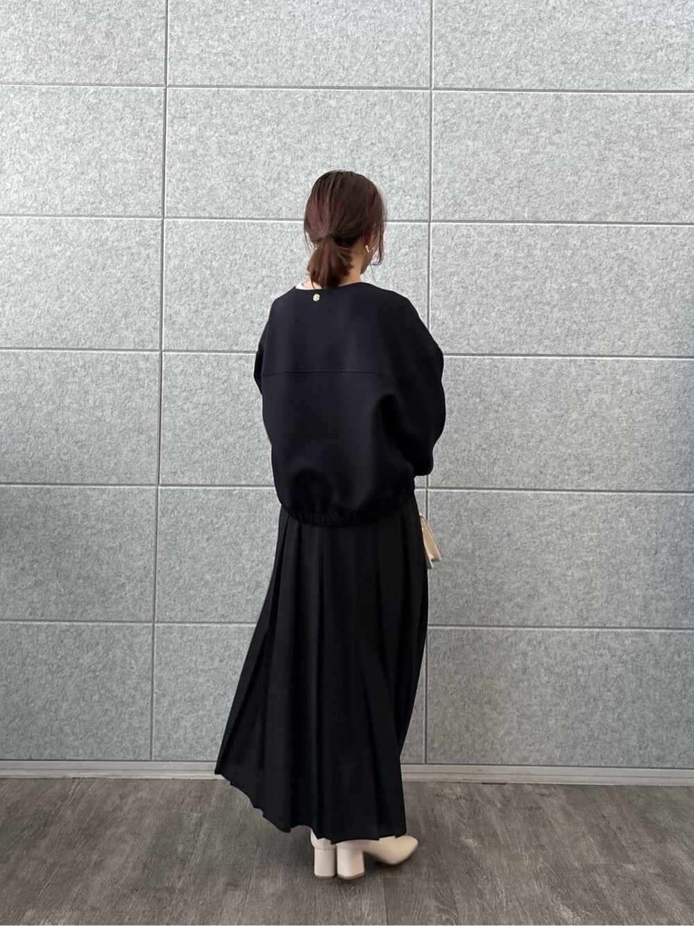ブラック系のブルゾン、ホワイト系のTシャツ/カットソー、ブラック系のスカートを着用したレディースの秋コーディネートの4枚目の写真