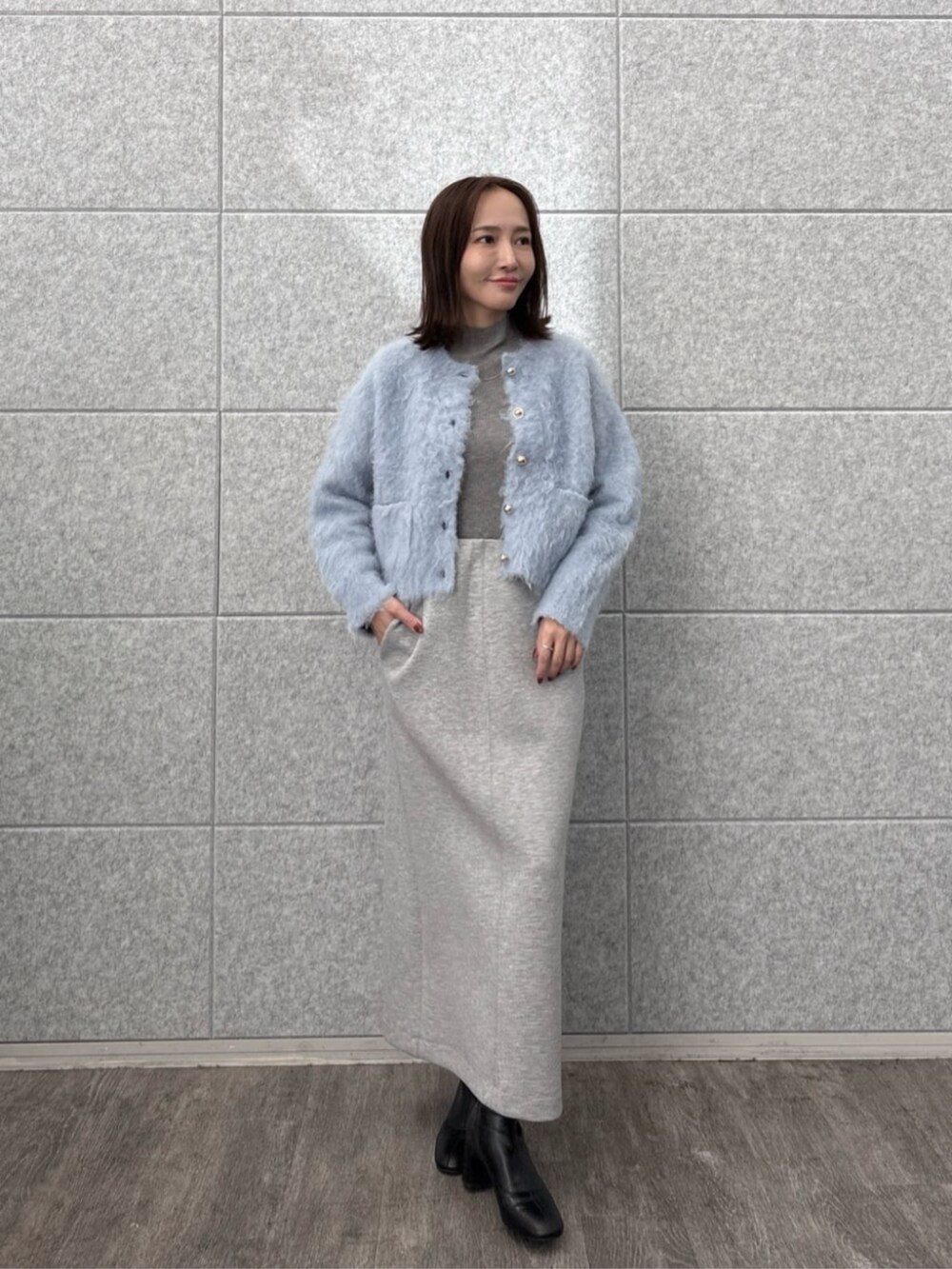グレー系のスカート、グレー系のニット/セーター、ブルー系のカーディガン/ボレロを着用したレディースの秋コーディネートの2枚目の写真