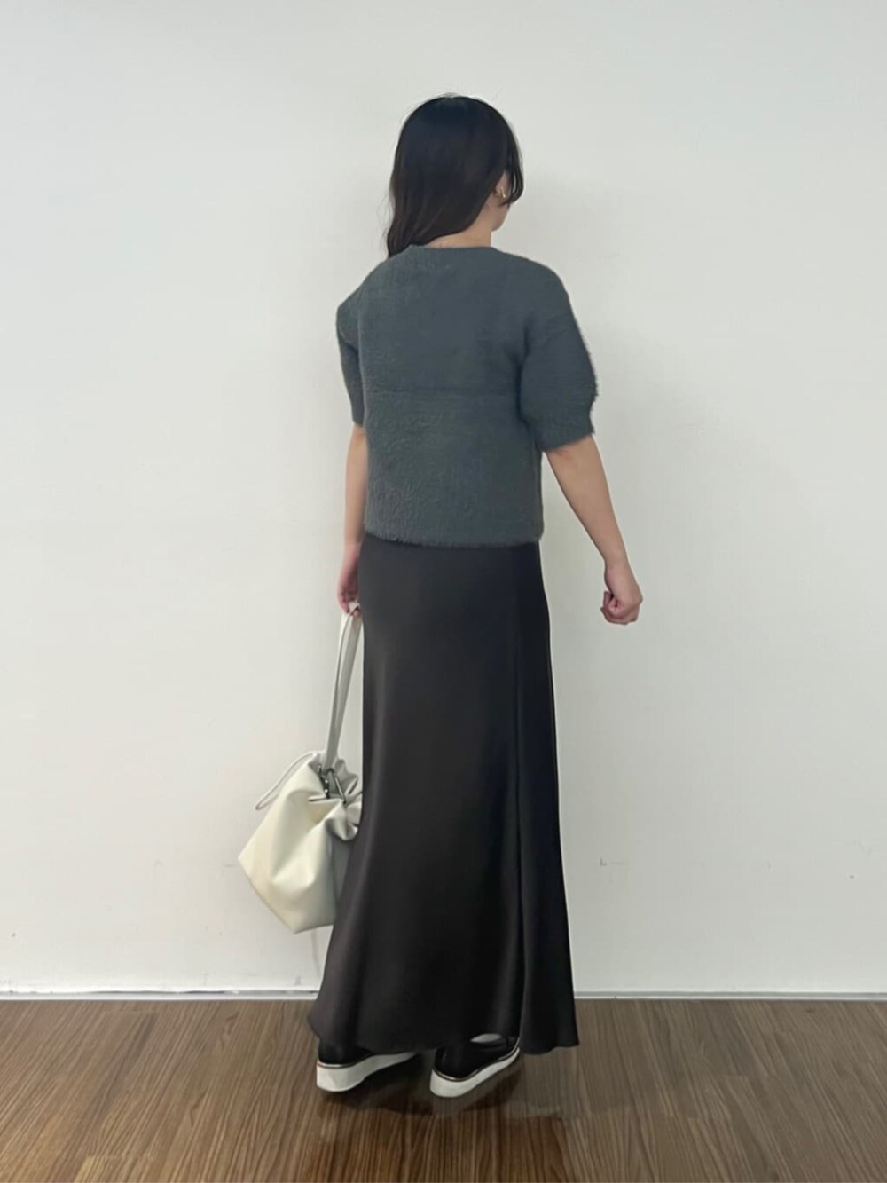 グレー系のニット/セーター、グレー系のスカートを着用したレディースの秋コーディネートの4枚目の写真