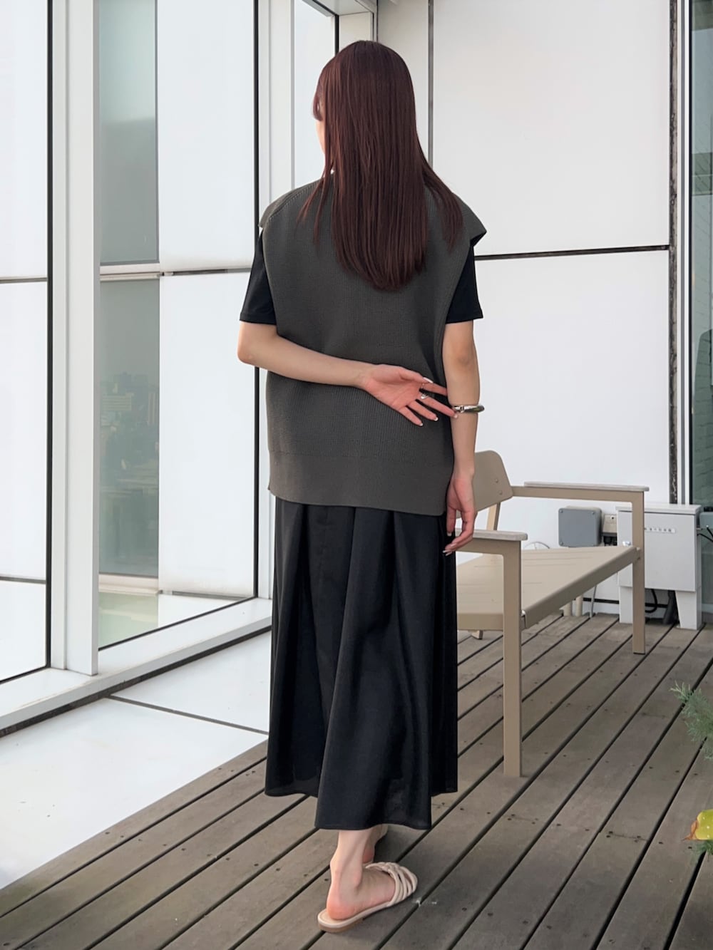 グレー系のベスト、ブラック系のスカート、ブラック系のTシャツ/カットソーを着用したレディースの春コーディネートの2枚目の写真