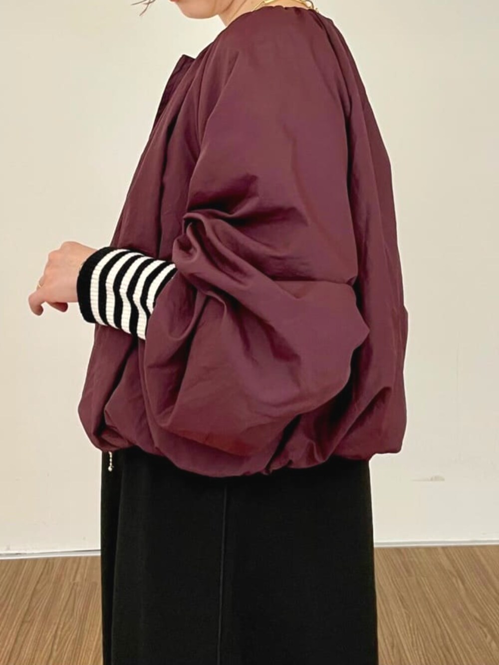 レッド系のブルゾン、ブラック系のワンピース、ベージュ系のニット/セーターを着用したレディースの秋コーディネートの6枚目の写真