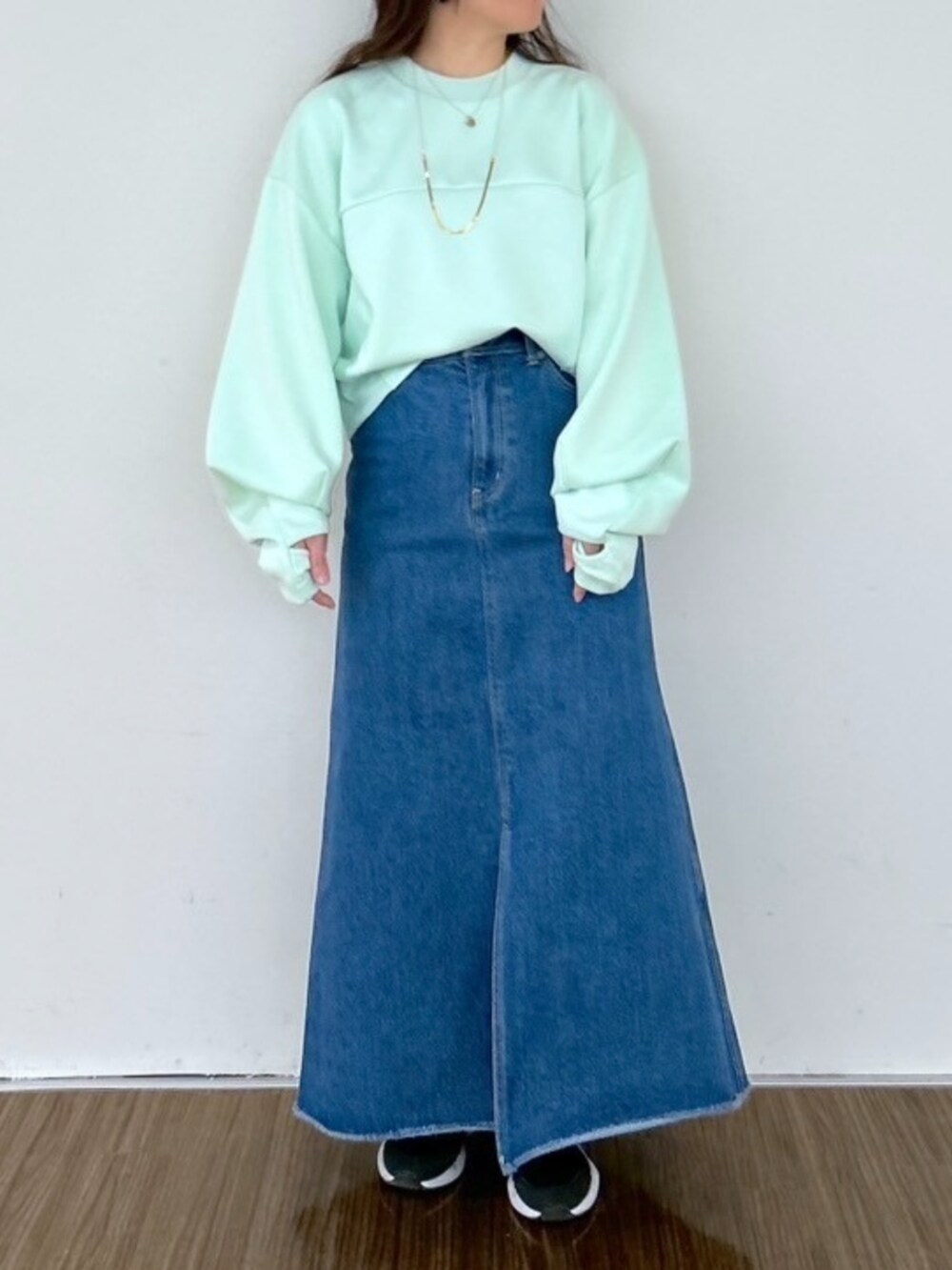 ブルー系のデニムスカート、グリーン系のスウェットを着用したレディースの春コーディネートの2枚目の写真