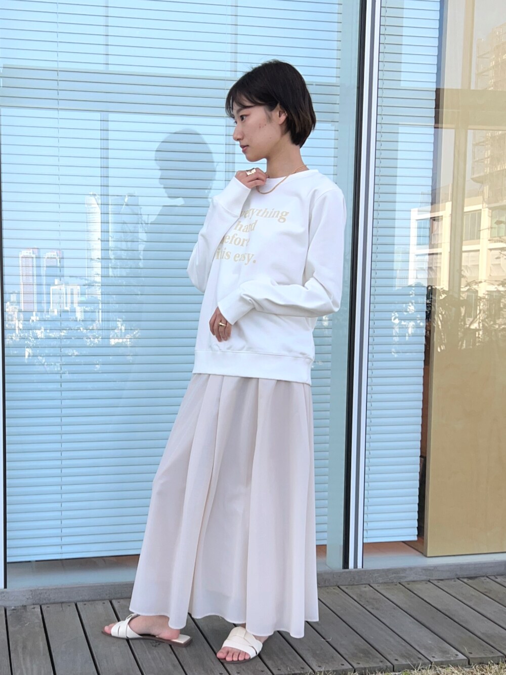 ベージュ系のスカート、ホワイト系のスウェットを着用したレディースの春コーディネートの2枚目の写真