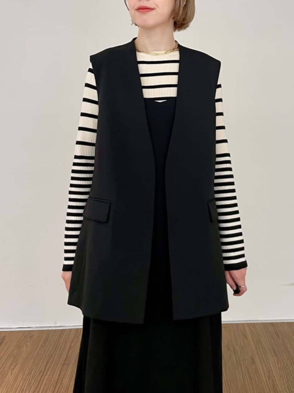 ブラック系のワンピース、ベージュ系のニット/セーター、ブラック系のベストを着用したレディースの秋コーディネートの5枚目の写真