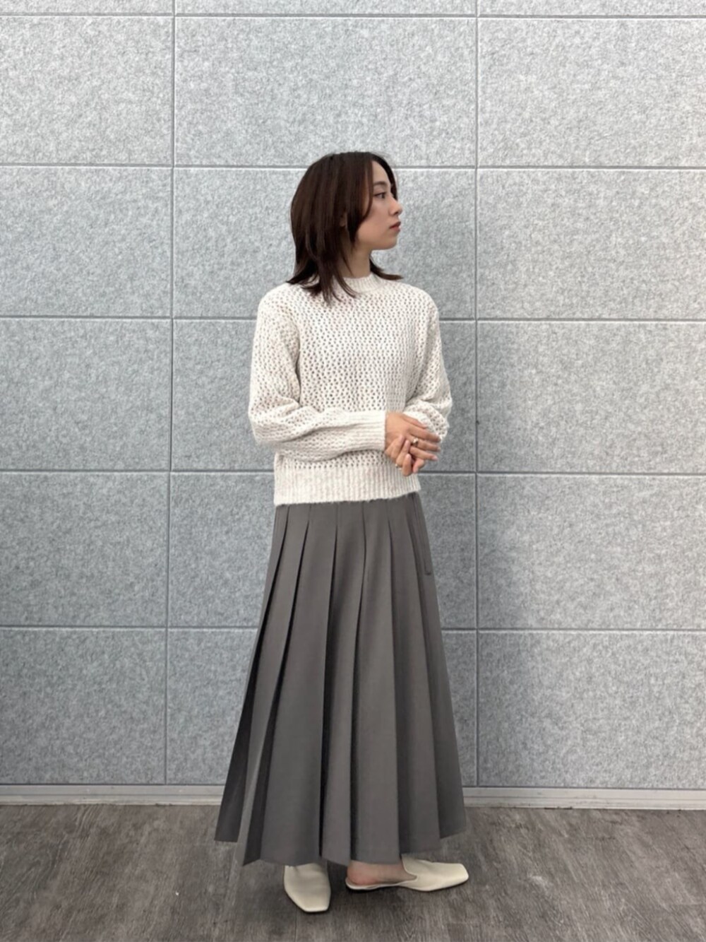 グレー系のスカート、ホワイト系のニット/セーターを着用したレディースの秋コーディネートの7枚目の写真