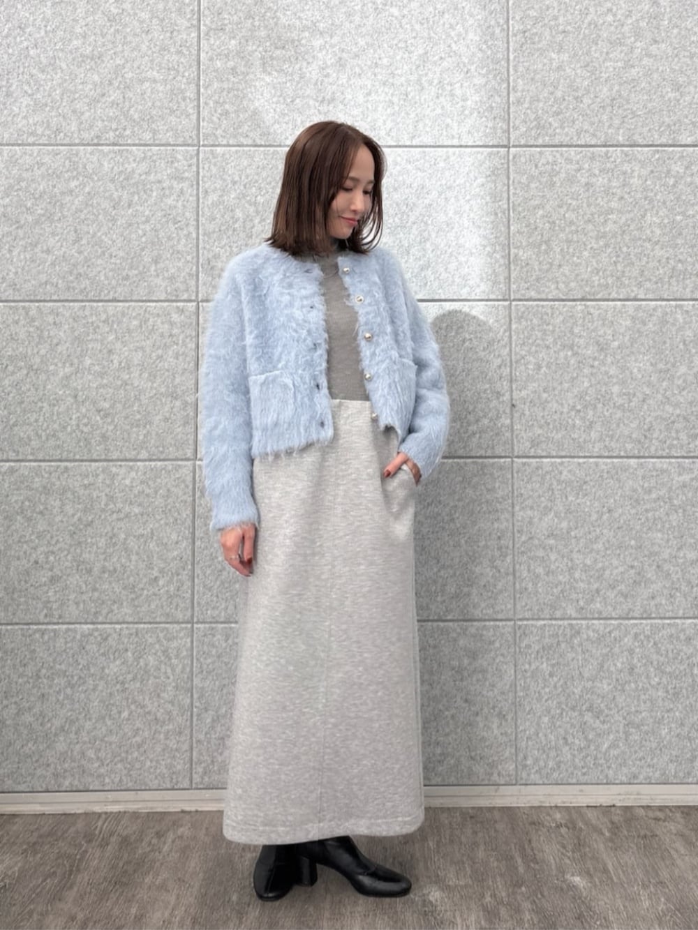 グレー系のスカート、グレー系のニット/セーター、ブルー系のカーディガン/ボレロを着用したレディースの秋コーディネートの3枚目の写真