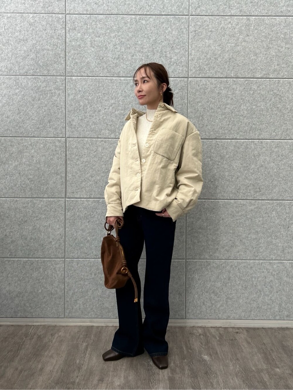 ベージュ系のブルゾン、ホワイト系のニット/セーター、ブルー系のデニムパンツを着用したレディースの冬コーディネートの4枚目の写真