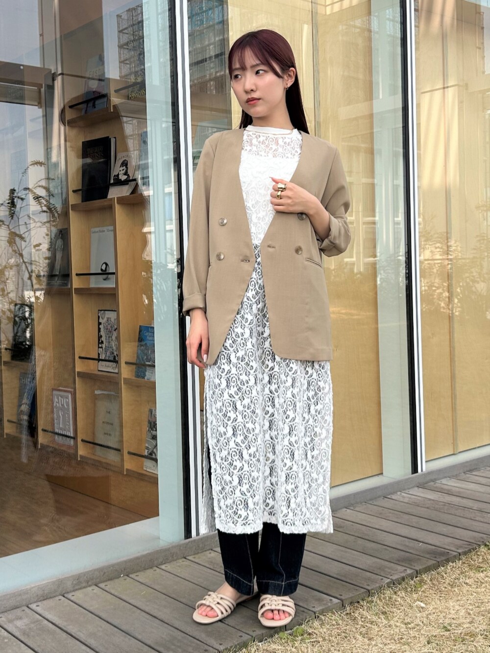 ブルー系のデニムパンツ、ベージュ系のノーカラージャケット、ホワイト系のタンクトップを着用したレディースの春コーディネートの3枚目の写真