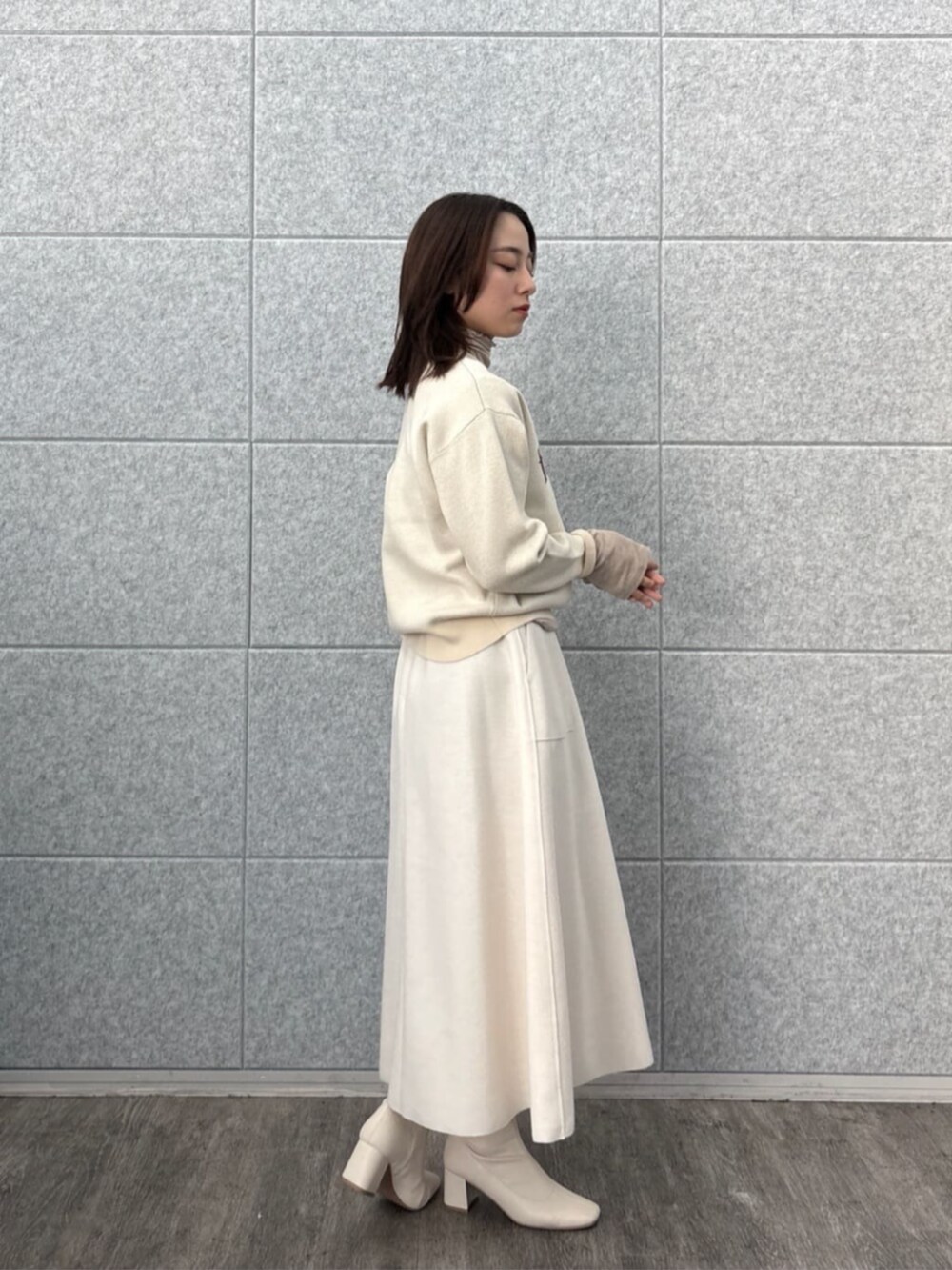 ホワイト系のスカート、ホワイト系のニット/セーター、ベージュ系のTシャツ/カットソーを着用したレディースの秋コーディネートの4枚目の写真