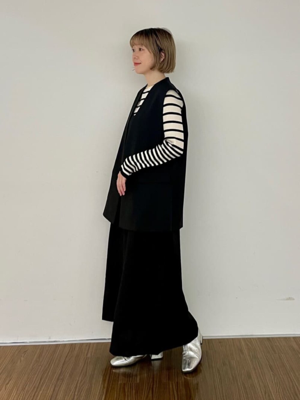 ブラック系のワンピース、ベージュ系のニット/セーター、ブラック系のベストを着用したレディースの秋コーディネートの3枚目の写真