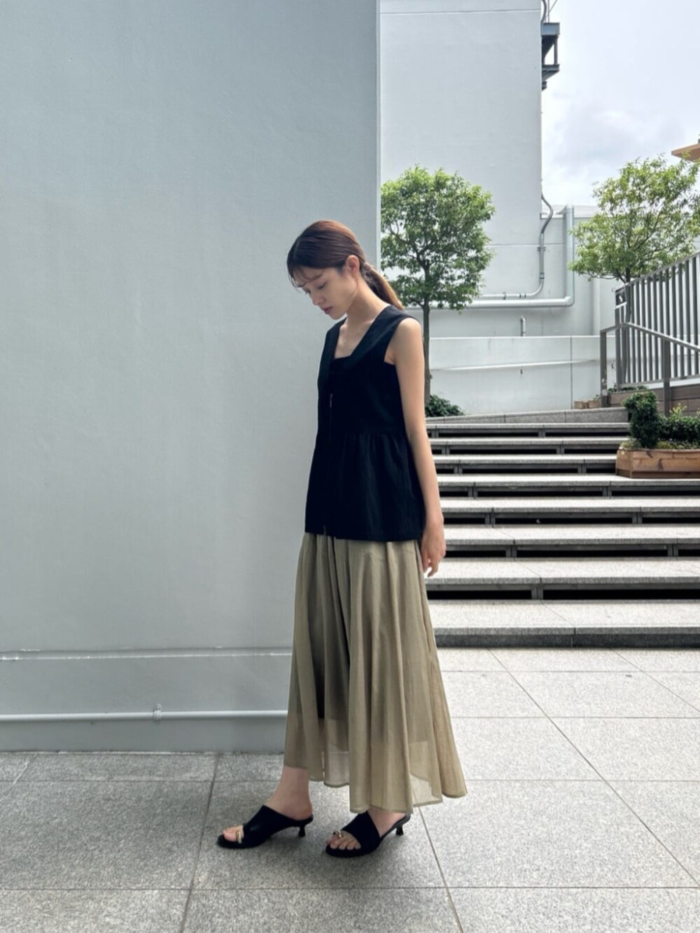 グリーン系のスカート、ブラック系のタンクトップ、ブラック系のシャツ/ブラウスを着用したレディースの夏コーディネートの2枚目の写真