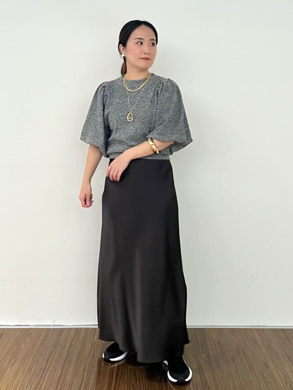 グレー系のスカート、ブラック系のニット/セーターを着用したレディースの秋コーディネートの2枚目の写真