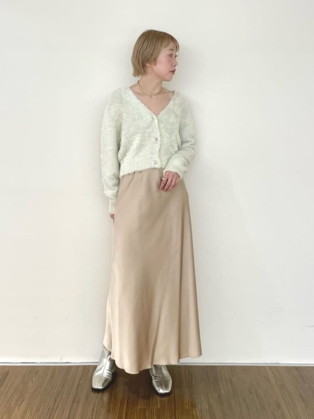 ベージュ系のスカート、ホワイト系のカーディガン/ボレロを着用したレディースの冬コーディネートの2枚目の写真
