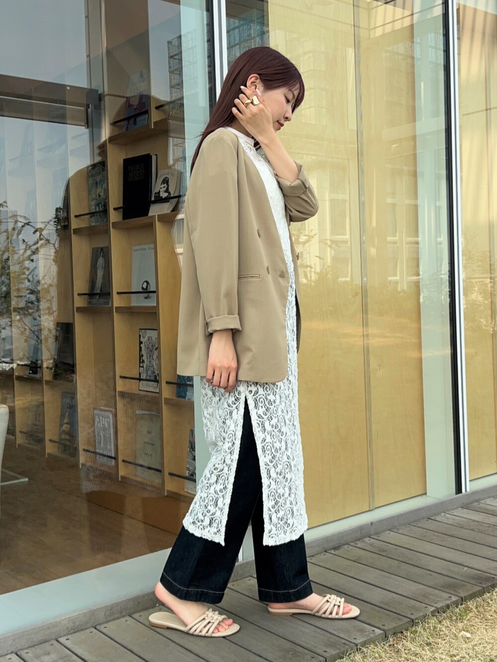 ブルー系のデニムパンツ、ベージュ系のノーカラージャケット、ホワイト系のタンクトップを着用したレディースの春コーディネートの4枚目の写真