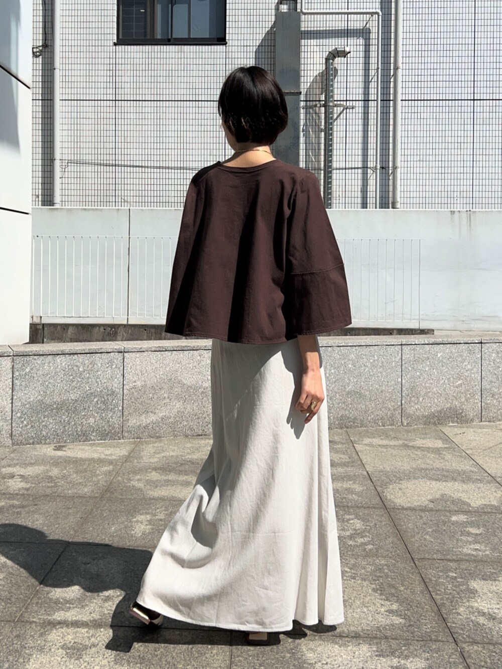 ホワイト系のスカート、ブラウン系のTシャツ/カットソーを着用したレディースの春コーディネートの4枚目の写真