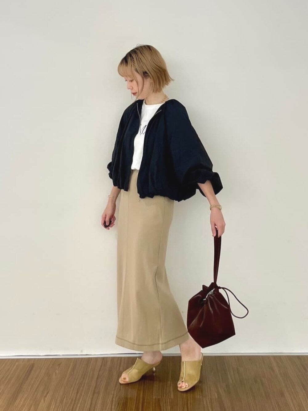 ブラック系のブルゾン、ブラウン系のスカート、ホワイト系のTシャツ/カットソーを着用したレディースの秋コーディネートの4枚目の写真