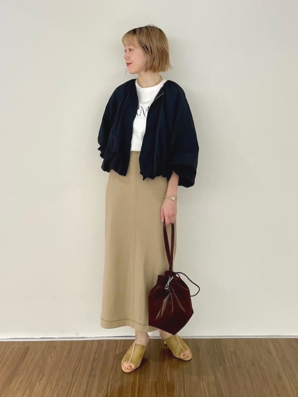 ブラック系のブルゾン、ブラウン系のスカート、ホワイト系のTシャツ/カットソーを着用したレディースの秋コーディネートの2枚目の写真