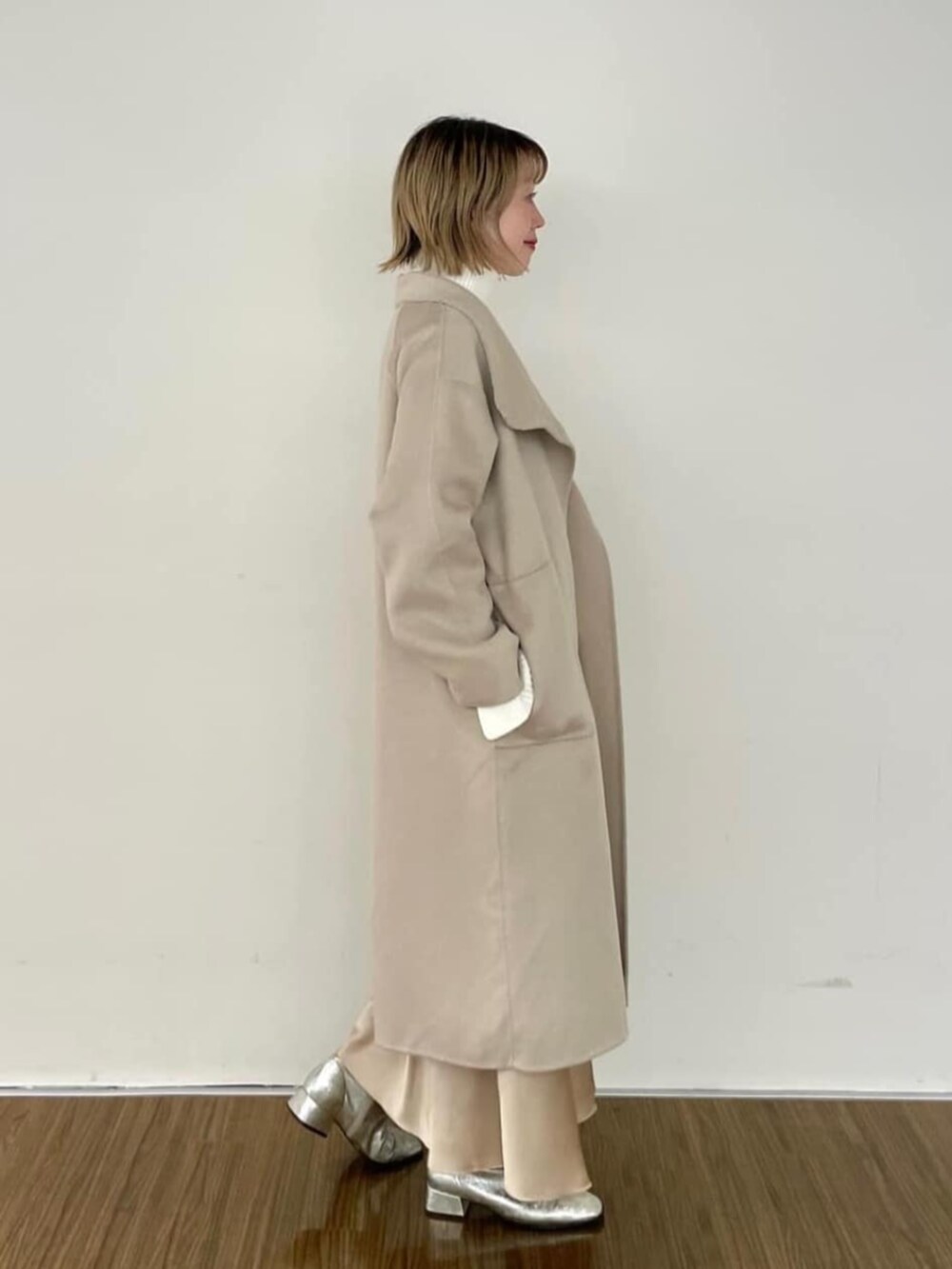 ベージュ系のスカート、ホワイト系のニット/セーター、ベージュ系のその他アウターを着用したレディースの秋コーディネートの4枚目の写真