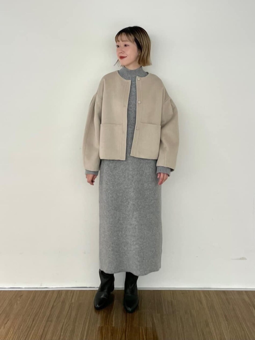 グレー系のワンピース、ベージュ系のノーカラーコートを着用したレディースの秋コーディネートの2枚目の写真