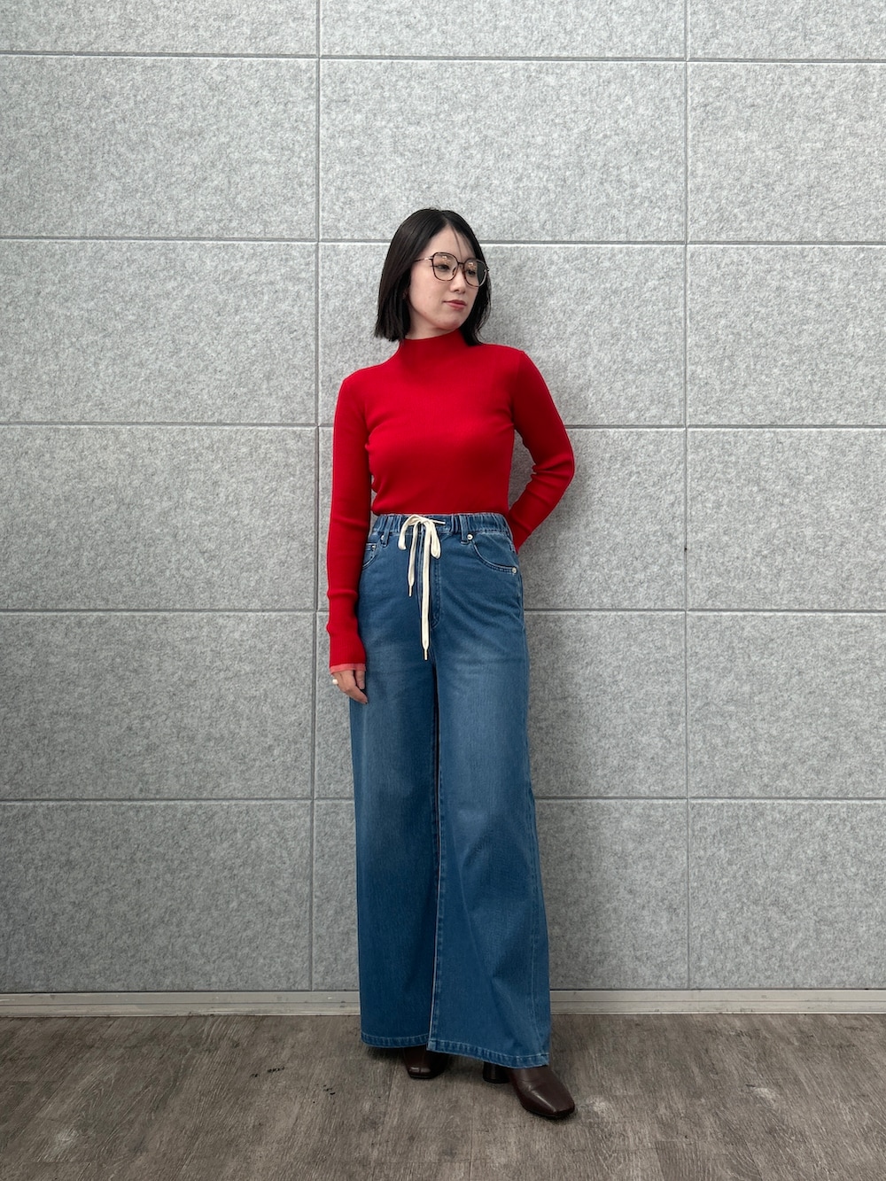 レッド系のニット/セーター、ブルー系のデニムパンツを着用したレディースの夏コーディネートの2枚目の写真