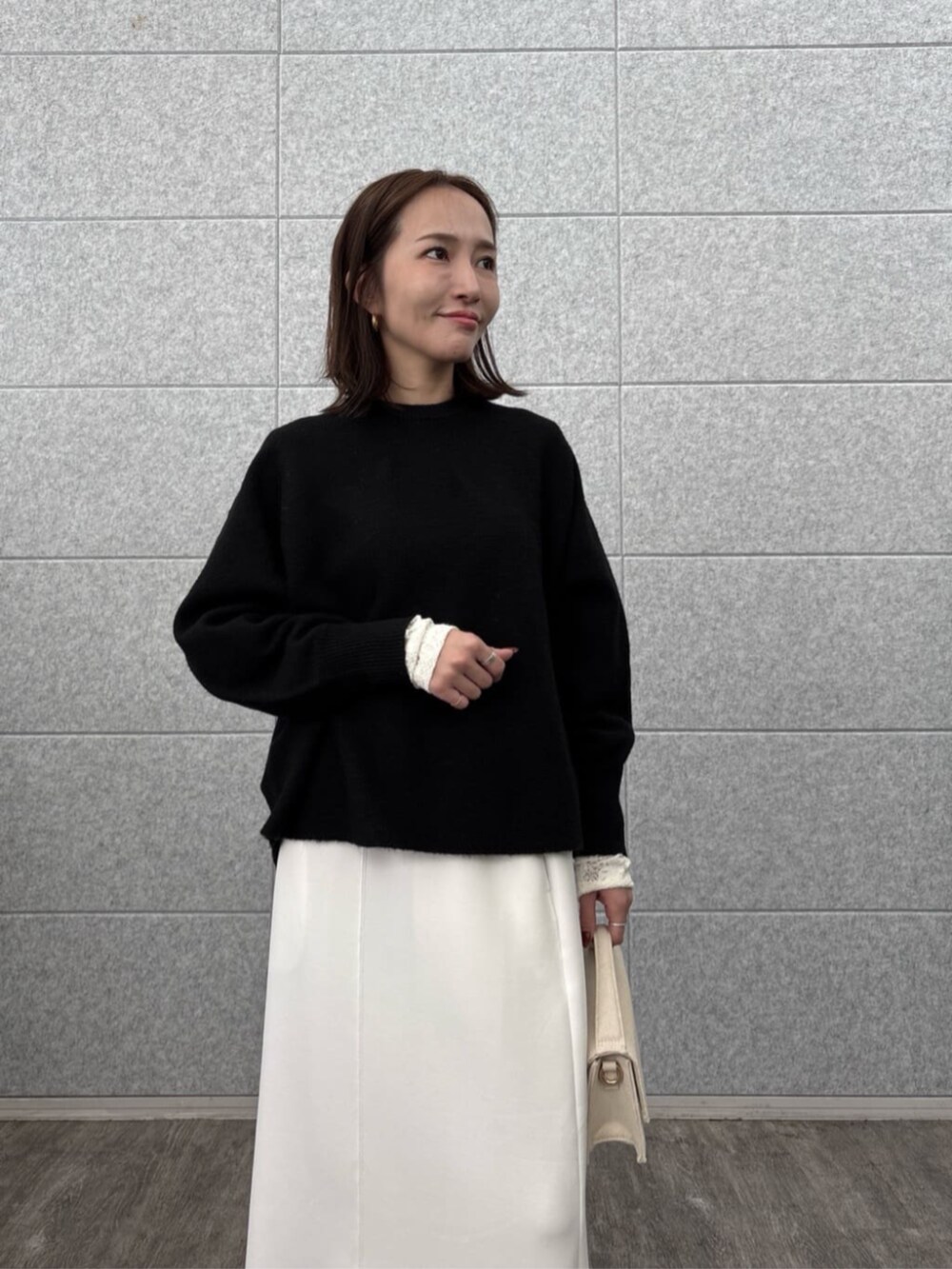 ホワイト系のスカート、ホワイト系のTシャツ/カットソー、ブラック系のニット/セーターを着用したレディースの秋コーディネートの5枚目の写真