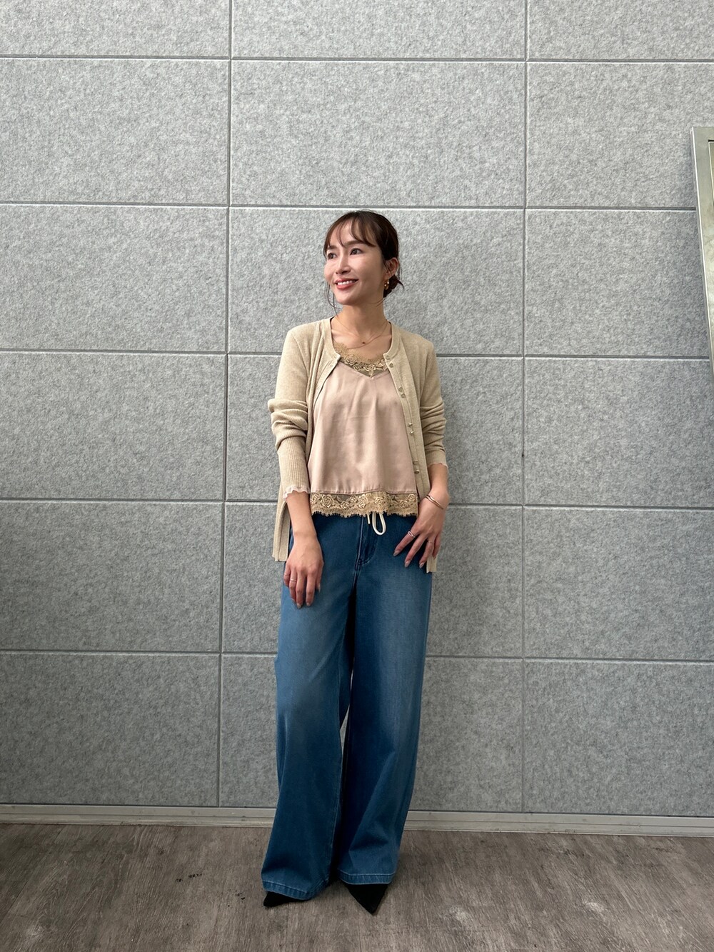 ベージュ系のカーディガン/ボレロ、ベージュ系のタンクトップ、ブルー系のデニムパンツを着用したレディースの秋コーディネートの5枚目の写真