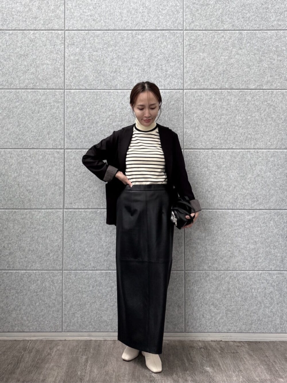 ブラック系のテーラードジャケット、ホワイト系のニット/セーターを着用したレディースの秋コーディネートの2枚目の写真