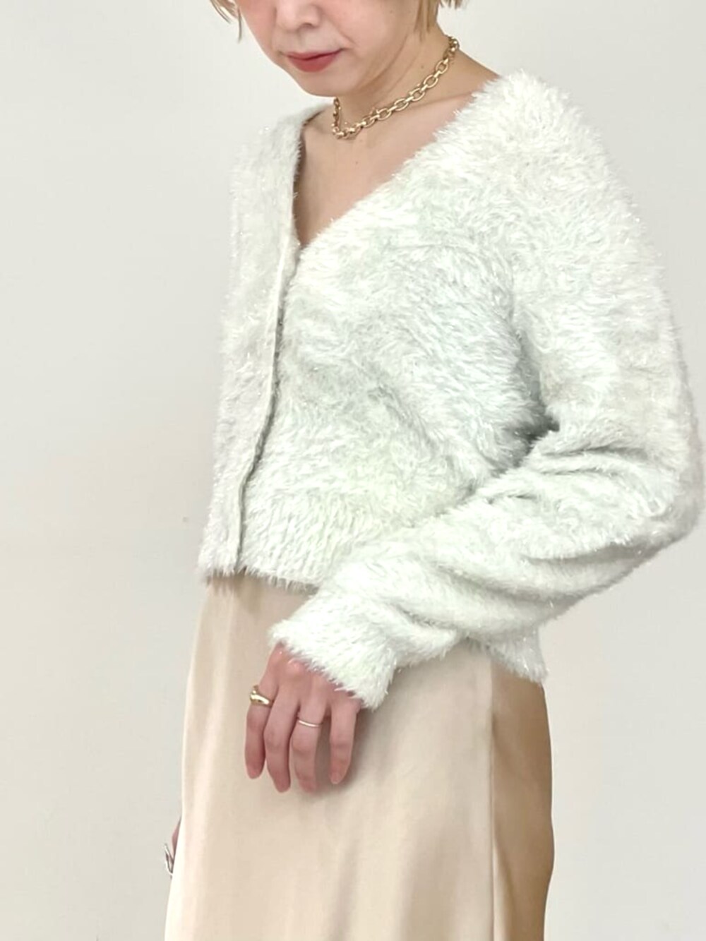 ベージュ系のスカート、ホワイト系のカーディガン/ボレロを着用したレディースの冬コーディネートの5枚目の写真