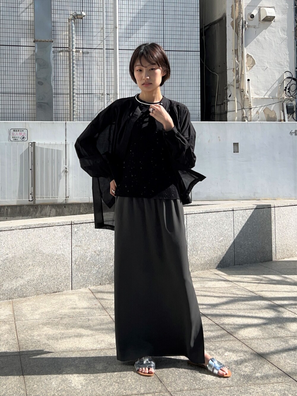 ブラック系のニット/セーター、グレー系のスカート、ブラック系のシャツ/ブラウスを着用したレディースの春コーディネートの3枚目の写真