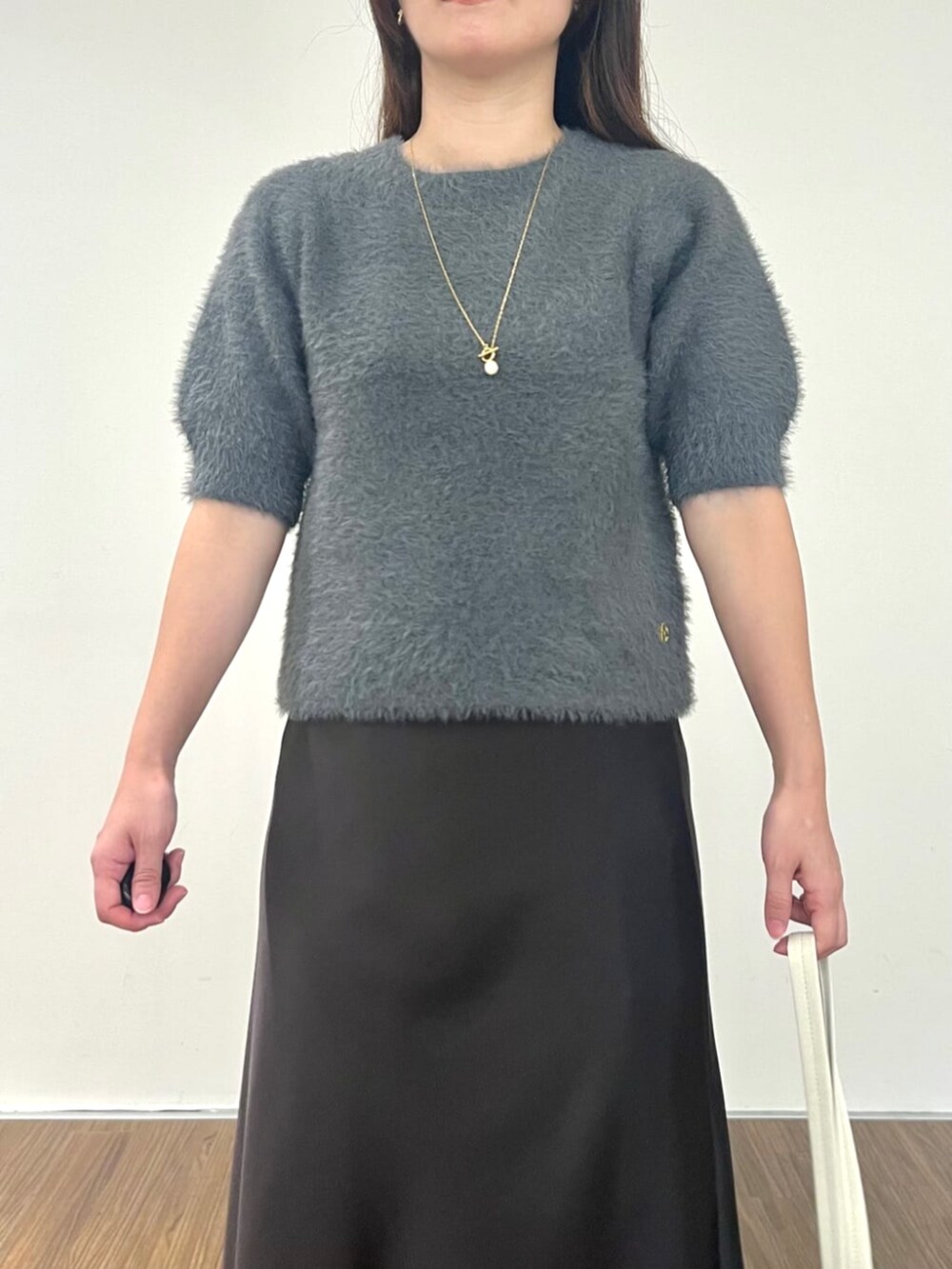 グレー系のニット/セーター、グレー系のスカートを着用したレディースの秋コーディネートの6枚目の写真