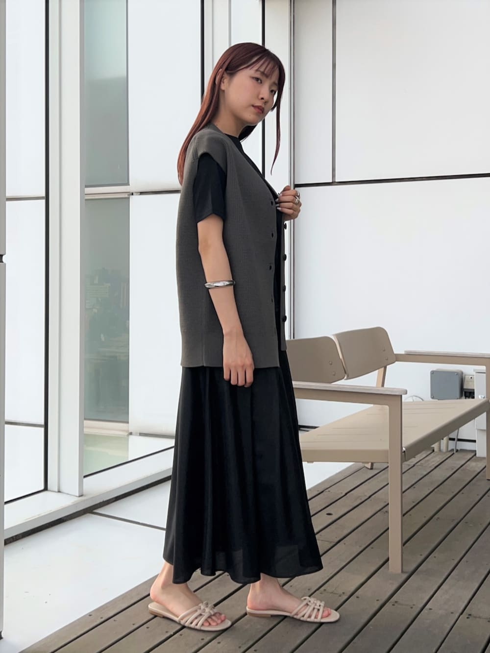 グレー系のベスト、ブラック系のスカート、ブラック系のTシャツ/カットソーを着用したレディースの春コーディネートの3枚目の写真