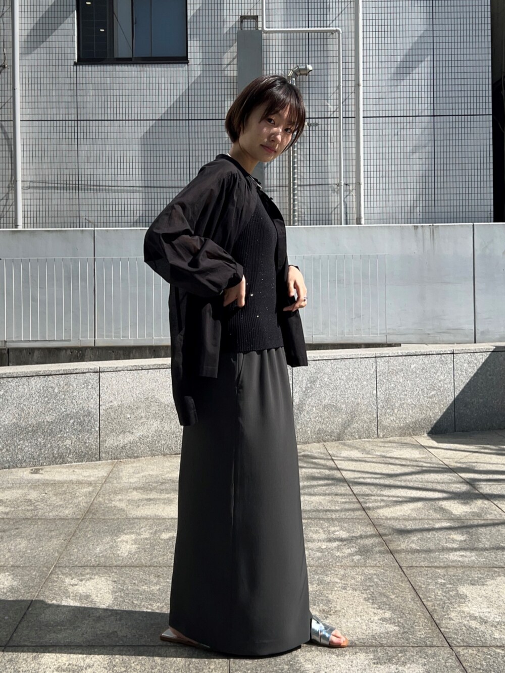 ブラック系のニット/セーター、グレー系のスカート、ブラック系のシャツ/ブラウスを着用したレディースの春コーディネートの6枚目の写真