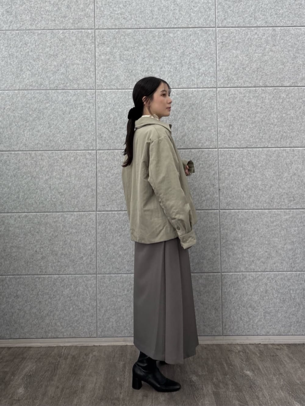 グレー系のスカート、ホワイト系のTシャツ/カットソー、グリーン系のブルゾンを着用したレディースの秋コーディネートの2枚目の写真
