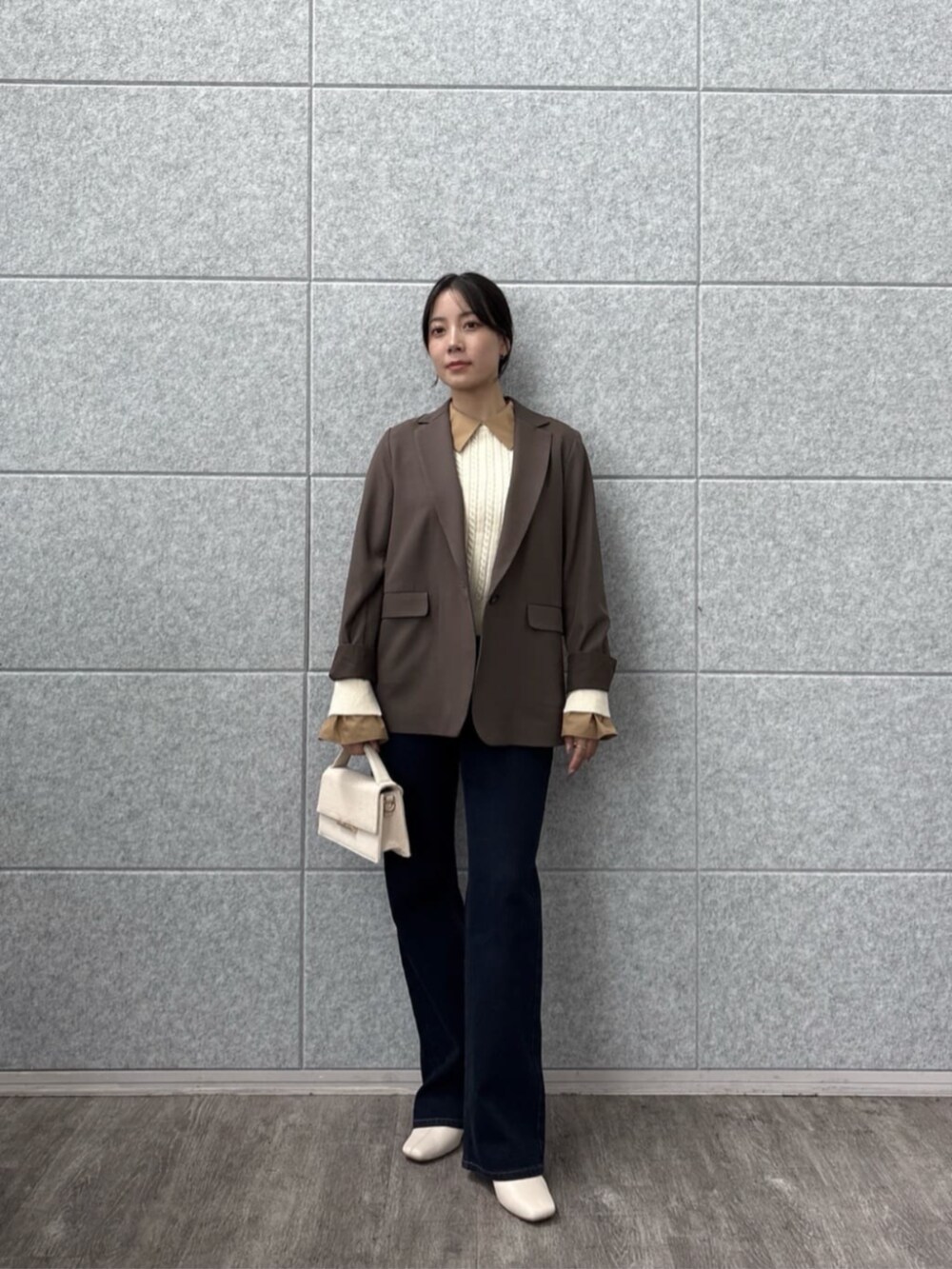 ブラウン系のテーラードジャケット、ブルー系のデニムパンツ、ホワイト系のニット/セーターを着用したレディースの秋コーディネートの6枚目の写真