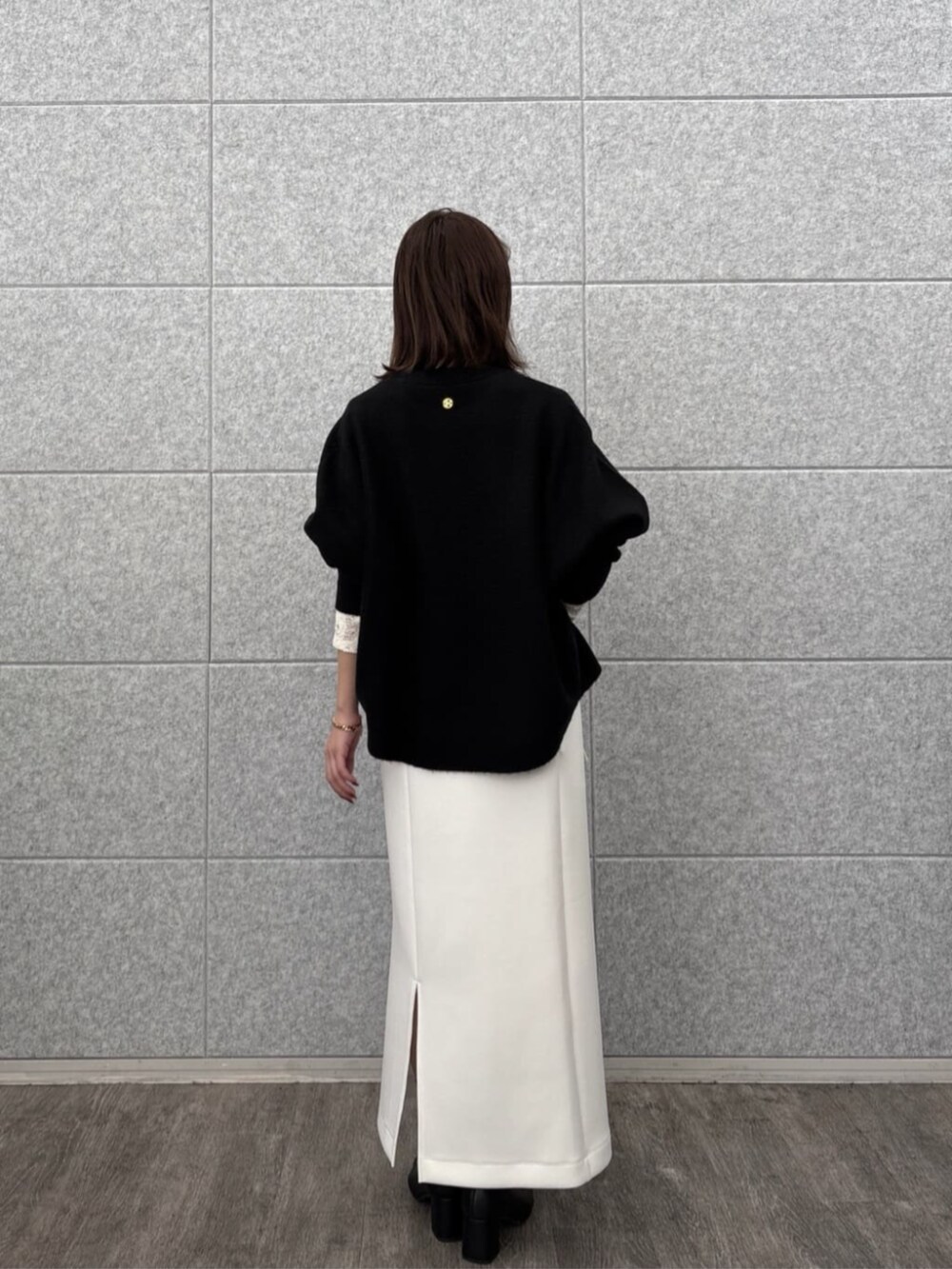 ホワイト系のスカート、ホワイト系のTシャツ/カットソー、ブラック系のニット/セーターを着用したレディースの秋コーディネートの4枚目の写真